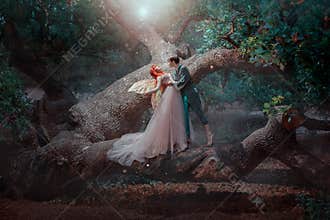 sexy man elf in love embraces gentle fantasy woman fairy. Family standing on branch of green tree. Red hair lady in