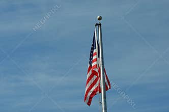 American Flag Waving on Flagpole Against Blue Sky