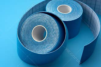 Blue Adhesive Physio or Kinesiology Tape Rolls on Matching Background Concept for Supportive Athletic Care, Enhancing Physical