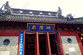 The plaque of the City God Temple has golden letters and borders, black tiles, a dragon head carved on the roof, a red-lacquered