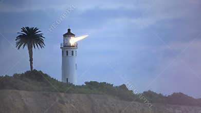 Cinemagraph of lighthouse with beaming light on the coast in the night