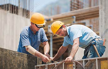 Builders cooperating on cement formwork frames