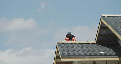 The builder is working on the roof of the house - laying shingles
