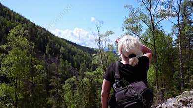 A woman looks into the distance at the sky and mountains.