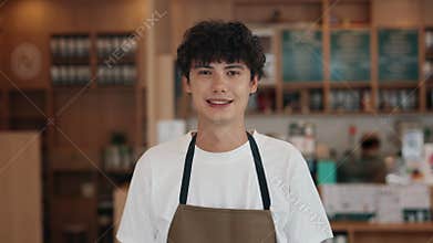 Portrait of young waiter wearing apron and white t-shirt smiling in coffeeshop