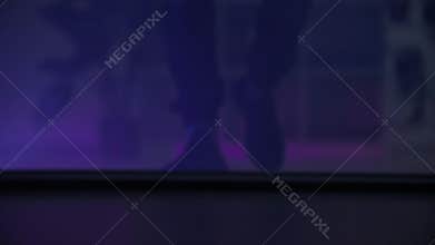 crime and robbery concept, male legs walking in dark room with flashing lights in background, close up