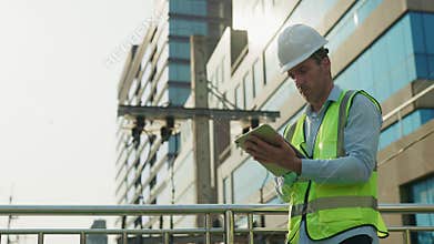 Man construction engineer examines project via tablet on footbridge