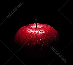 Fresh red apple with droplets of water against black background