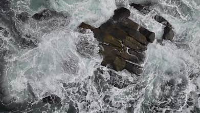 Slow motion surf surrounds coastal rocks