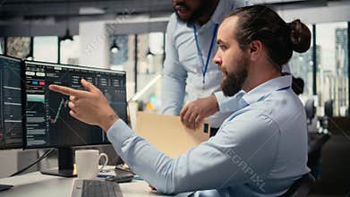 Coworkers collaborate on trading strategies in office, review stock market data
