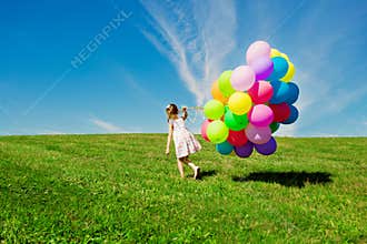 Little girl holding colorful balloons. Child playing on a green
