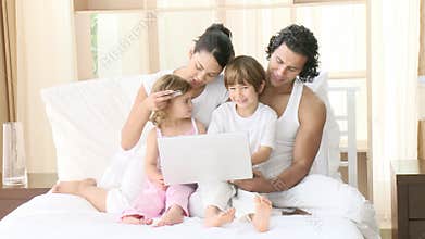 Family buying online with a laptop in bedroom