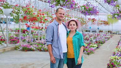 A family of aspiring flower sellers stands in a greenhouse,