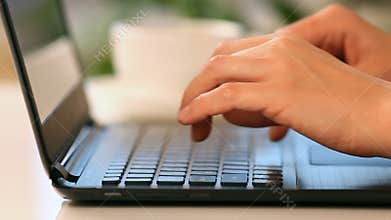 Hands typing on a laptop keyboard