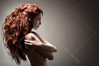 Beautiful woman with curly hairstyle on gray background