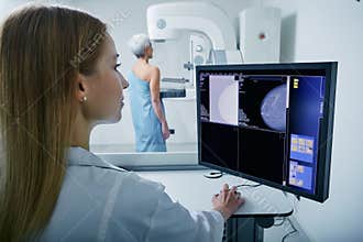 Medical technician doing mammogram exam to female patient. Mature woman undergoing breast screening or mammography