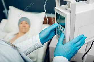 Oncologist turning on device IV drip chemotherapy for an elderly woman with cancer. Patient receiving chemotherapy