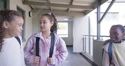 African American teen girls standing with backpacks at school as friends running up between classes