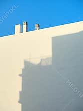 White building façade with chimneys and a blue sky