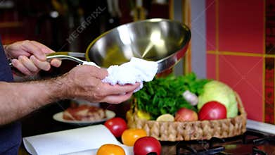 Stainless steel pan wiped with kitchen towel by chef before cooking on clean countertop in professional kitchen close up
