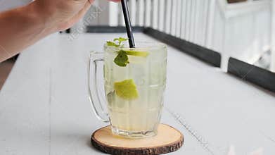 Man drinking mint lime refreshing iced drink lemonade in glass mug with a straw in Phuket, Thailand. Mojito mocktail