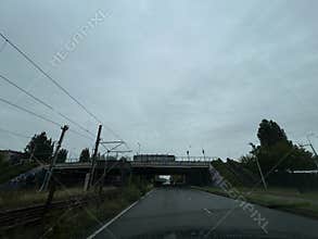 Overcast road under railway bridge with tram lines, empty urban lanes, stair