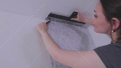 Trimming wallpaper in the corners of a room after wallpapering. Trimming excess paper.