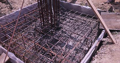 Close Up of Reinforced Steel Rebar Foundation with Workers Pouring Wet Concrete, Building Footing Construction