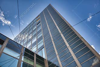 Modern glass office building with clear blue sky and reflection viewed from street level perspective urban architecture