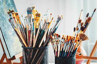 Artistic equipment in studio: painting, easel, paintbrushes and paints.