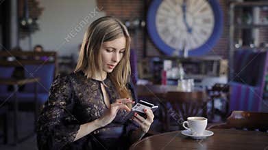 Beautiful business woman orders tickets for an airplane online, sitting in a cafe. The girl uses internet banking and
