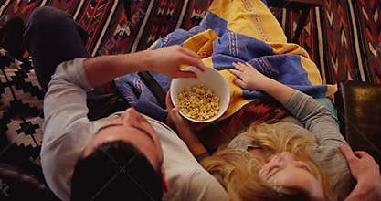 Couple relaxing on sofa watching tv in living room