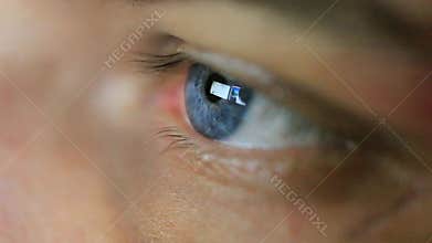 Close up of mans eye looking on computers monitor