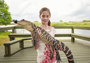 Cute girl holding a crocodile near florida everglades