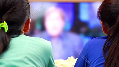 Two happy teenage girls watching news on smart tv