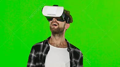Young man with VR virtual reality headset on his head. Green screen. Close up