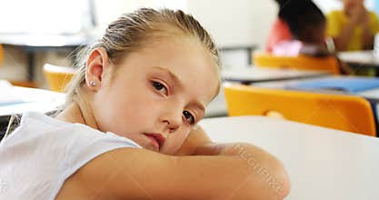 Sad girl lying on desk in class