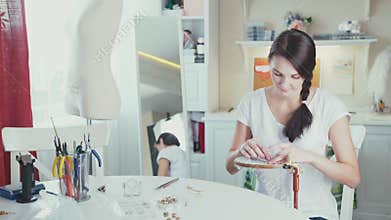 The girl embroiders using decorative stones and hoops.