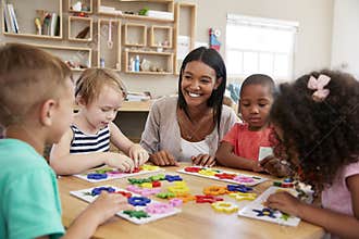 Teacher And Pupils Using Flower Shapes In Montessori School