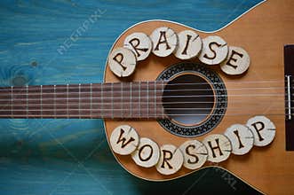 Guitar on wood with words: PRAISE and WORSHIP
