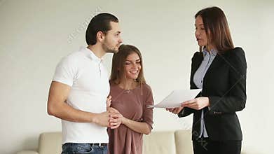 Young happy couple discussing contract and shaking hands with contractor