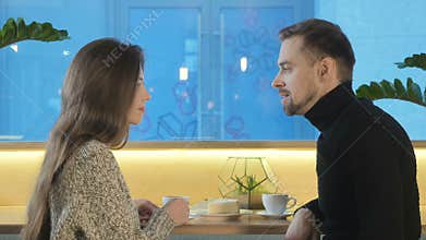 A young couple is drinking coffee in a cafe