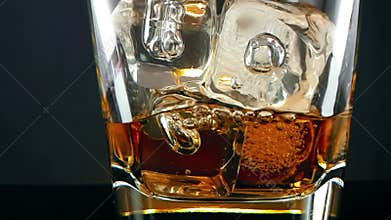 whiskey in the drinking glass with ice cubes on black background, time of relax drink with whisky