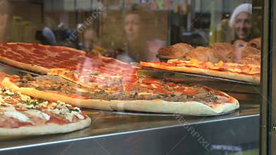 Reflections of People walking by a Pizzeria