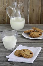 Chocolate and cranberry cookies with milk on wooden table