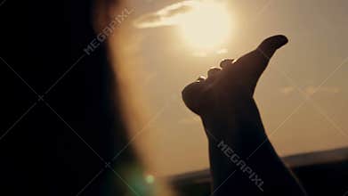 Girl looks at the sun through her hand