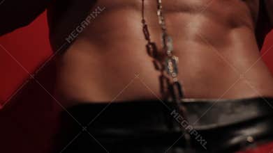 Muscular body of a stripper. Handcuffs and a blade sliding on a naked torso.