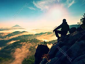 Hiker man take a rest on mountain peak. Man lay on summit, bellow autumn valley.