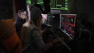 Team of hackers, hacking computers, working in dark room.