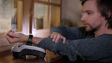 Customer paying with NFC technology by smart watch contactless on terminal in modern cafe